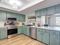 A bright, fully equipped kitchen with stainless steel appliances, wood floors, and light green cabinets at 9425 Sterling Ln, Port Richey, FL 34668