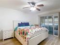 Bright main bedroom featuring wood floors, a large bed, and a sliding glass door to the lanai at 9425 Sterling Ln, Port Richey, FL 34668