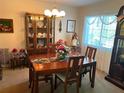 This well-lit dining room features a chandelier, a china cabinet, and a classic grandfather clock near a window at 9474 Nakoma Way # E, Weeki Wachee, FL 34613