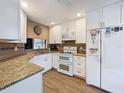 Bright kitchen featuring white cabinetry, stainless appliances, and granite countertops, complemented by wood flooring at 11622 White Ash Dr, New Port Richey, FL 34654