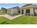 Close up exterior view of single-story home with manicured lawn and attached one car garage at 11725 Spring Tree Ln, Port Richey, FL 34668