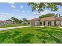 Exterior view of single-story home with lush green lawn and driveway in quiet neighborhood at 11725 Spring Tree Ln, Port Richey, FL 34668