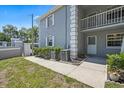 Exterior view of condo building with light blue siding, white trim, second story balcony, and manicured bushes at 12141 Spartan Way # 102, Hudson, FL 34667