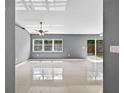 Bright living room with shiny tile flooring, fan, and slider leading to the backyard at 2476 Magellan Ave, Spring Hill, FL 34608