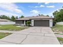 View of the well-maintained single-story home with a brown roof, a front lawn and paved driveway at 3498 Plaza Ave, Spring Hill, FL 34608