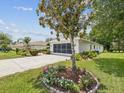 Home exterior showing a driveway, lawn, and charming flower garden at 489 Tournament Dr, Spring Hill, FL 34608