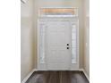 Welcoming front door with sidelights and a transom window, complemented by dark wood-look flooring at 5048 Teather St, Spring Hill, FL 34608
