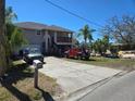 Beige two-story home with a front-facing garage, wooden staircase to the porch, and a spacious concrete driveway at 5420 Bay Blvd, Port Richey, FL 34668