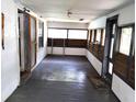 Enclosed front porch featuring gray wood floors, white walls, and multiple windows at 5748 Montana Ave, New Port Richey, FL 34652
