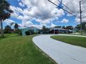 Beautiful curb appeal with a sprawling driveway, lush green lawn, and vibrant landscaping surrounding this well-maintained home at 6737 Clark St, Hudson, FL 34667