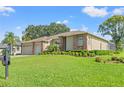 Beautiful one-story home showcases lush landscaping, a brick-accented facade, and a well-kept lawn at 7328 Blue Skies Dr, Spring Hill, FL 34606