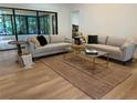 Bright living room featuring modern sofas, a jute rug, a glass-top coffee table, and floor-to-ceiling sliding glass doors at 8209 Golf Club Ct, Hudson, FL 34667