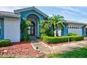 Inviting front entrance with arched doorway, mature landscaping, and a charming statue, exuding elegance at 8540 Caitlin Ct, Hudson, FL 34667