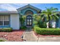 Inviting front entrance with arched doorway, mature landscaping, and a charming statue, exuding elegance at 8540 Caitlin Ct, Hudson, FL 34667