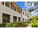 Side view of a gray townhouse with red shutters and a landscaped walkway at 9420 Georgian Park Ln # 106, Tampa, FL 33626
