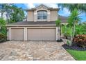 Inviting two-story home with a three-car garage, brick paver driveway, and mature landscaping at 10925 Oyster Bay Cir, New Port Richey, FL 34654
