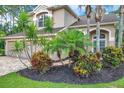 Beautifully landscaped front yard with mature trees, colorful shrubs, and a brick paver driveway at 10925 Oyster Bay Cir, New Port Richey, FL 34654