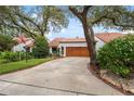Inviting home showcasing a lush lawn, mature trees, and a neatly paved driveway at 11505 Cerca Del Rio, Temple Terrace, FL 33617