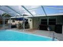 Backyard patio featuring a screened in pool, dining table, and a grill, perfect for outdoor entertaining at 11810 Oceanside Dr, Port Richey, FL 34668