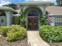 Inviting entrance adorned with lush greenery, climbing vines, and a charming stone pathway leading to double doors at 1231 Etta Ave, Spring Hill, FL 34609