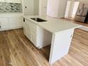 Modern kitchen island with a sink, white cabinets and light countertops over wood-look flooring at 14586 Mocking Wren Rd, Weeki Wachee, FL 34614