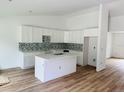 Bright kitchen with white cabinets, a center island, modern backsplash and wood-look flooring at 14586 Mocking Wren Rd, Weeki Wachee, FL 34614