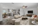 Bright open-plan living area with neutral decor, modern furnishings, ceiling fan and wood-look flooring at 16104 Naples St, Brooksville, FL 34604