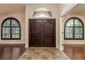 Grand entryway featuring dark, solid wood double doors, arched windows and beautiful tile and hardwood flooring at 1831 Cardamon Dr, Trinity, FL 34655
