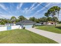 Lovely single-story home showcasing a long driveway, lush green lawn, and vibrant light blue exterior at 2027 Fentress Ct, Spring Hill, FL 34609