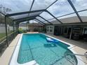 Sparkling screened-in pool area featuring comfortable patio seating and clear blue water at 3128 Montague Ave, Spring Hill, FL 34608