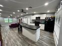 Open-concept kitchen with a large island, black countertops, white cabinets, stainless appliances, and black refrigerator at 8122 Matthew Dr, New Port Richey, FL 34653