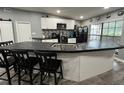 Modern kitchen boasts a large island with black countertops, white cabinets, and stainless steel appliances at 8122 Matthew Dr, New Port Richey, FL 34653