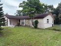 Side view of a single-story home with stone facade and chain link fence at 8516 Inwood Dr, Hudson, FL 34667
