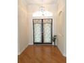 Inviting foyer featuring decorative double doors, a chandelier, and hardwood flooring at 9188 Mississippi Run, Weeki Wachee, FL 34613