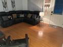 Comfortable living room with hardwood floors and a large black leather sectional couch and a doorway to the outside at 9536 Mayson St, New Port Richey, FL 34654