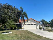 Charming single-story home with a red tile roof, lush landscaping, and a wide driveway at 4989 Clubview E Ct, Bradenton, FL 34203