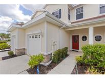 Two-story townhome with a red door, attached garage, and landscaping at 1127 Jonah Dr, North Port, FL 34289