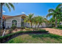 Single-story home with a tile driveway, lush landscaping, and palm trees at 4006 Caddie E Dr, Bradenton, FL 34203