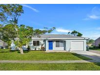 Newly renovated light blue house with a blue door, and a well-manicured lawn at 3875 Pan American Blvd, North Port, FL 34287