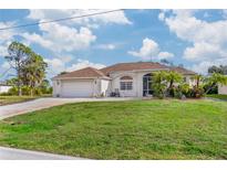 Single-story home with a two-car garage and lush lawn at 855 Boundary Blvd, Rotonda West, FL 33947