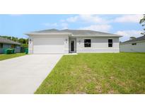 Newly built home with a white exterior and a grassy yard at 23246 Stelling Ave, Port Charlotte, FL 33980