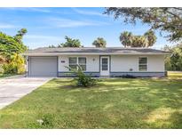 Charming single-story home with a well-maintained lawn and mature landscaping at 301 Lambert St, Port Charlotte, FL 33948