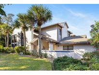 Stunning multi-level home with a landscaped yard and tiled wall, accented by swaying palm trees and a bright blue sky at 1654 Starling Dr # 201, Sarasota, FL 34231