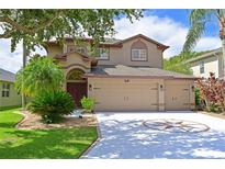 Two-story house with tan exterior, three car garage, and landscaped yard at 8108 Haven Harbour Way, Bradenton, FL 34212