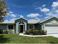 Quaint ranch home with light teal exterior and tidy landscaping at 23482 Moreland Ave, Port Charlotte, FL 33954