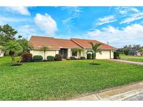 Charming single-story home boasts a tile roof, lush lawn, and tropical landscaping at 328 Eden Dr, Englewood, FL 34223