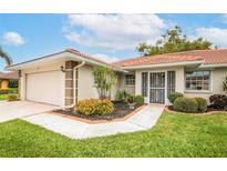 Charming single-story home with a well-manicured lawn, mature landscaping, and a terracotta tile roof at 1654 Waxwing Ct, Venice, FL 34293