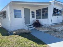 Mobile home with gray door, screened porch, and landscaping at 1834 Palm Springs St, Sarasota, FL 34234