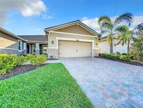 Charming home featuring a two-car garage, paver driveway, stone accents, and well-manicured landscaping at 8678 Rain Song Rd, Sarasota, FL 34238