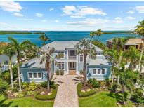 Stunning waterfront home with lush landscaping and a gray metal roof offering picturesque views of the bay at 757 Hideaway Bay Dr, Longboat Key, FL 34228